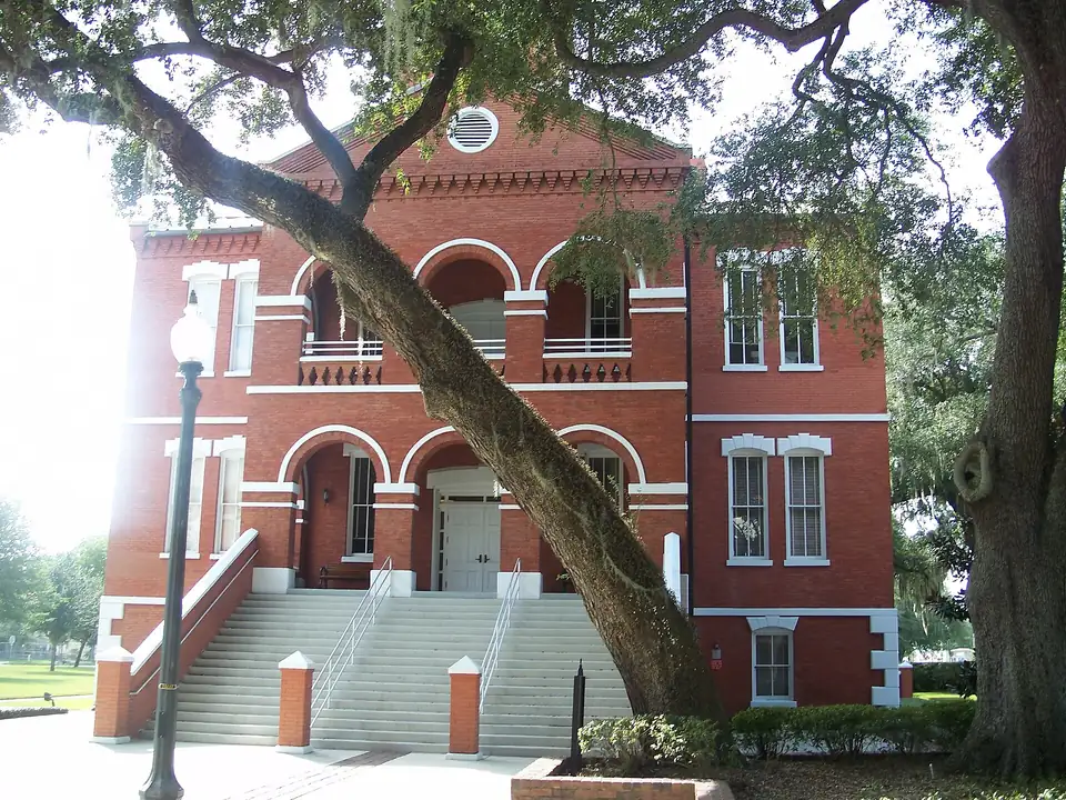 The red-brick historic Osceola County Courthouse in Kissimmee under the limbs of a large oak